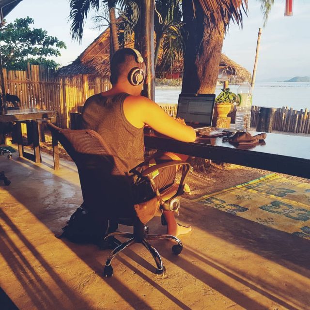 homme travaillant à un bureau sur une terrasse avec vue sur mer