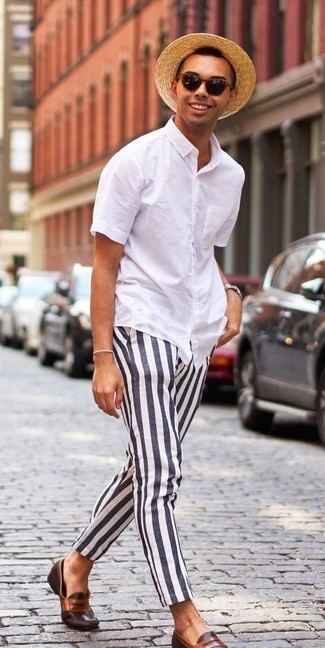 Homme traversant la rue avec une chemisette blanche, un pantalon à rayures, un chapeau et des mocassin
