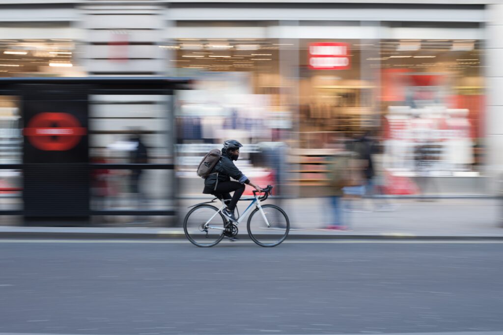 homme en vélo passant devant des magasins